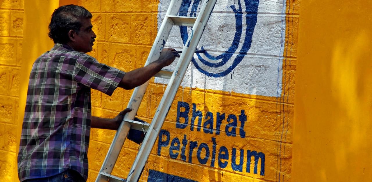 A man paints the logo of oil refiner Bharat Petroleum Corp (BPCL) on a wall on the outskirts of Kochi. Credit: Reuters Photo