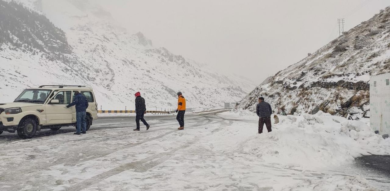 People walk on a snow-covered road after fresh snowfal near Atal Tunnel at Rohtang in Lahaul-Spiti district. Credit: PTI Photo