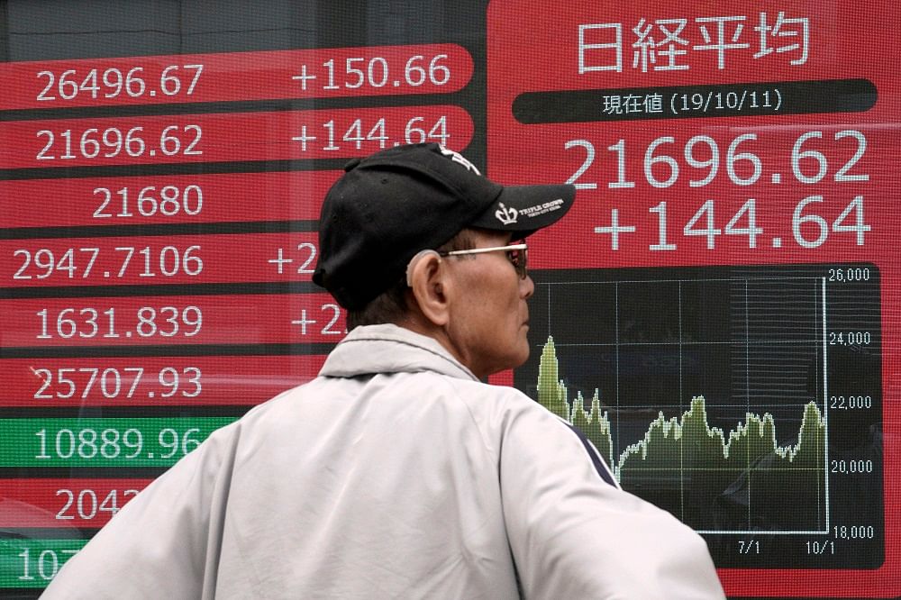A man looks at an electronic stock board showing Japan's Nikkei 225 index at a securities firm in Tokyo. Credit: AP Photo