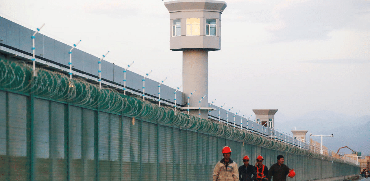 Workers walk by the perimeter fence of what is officially known as a vocational skills education centre in Dabancheng in Xinjiang. Credit: Reuters Photo