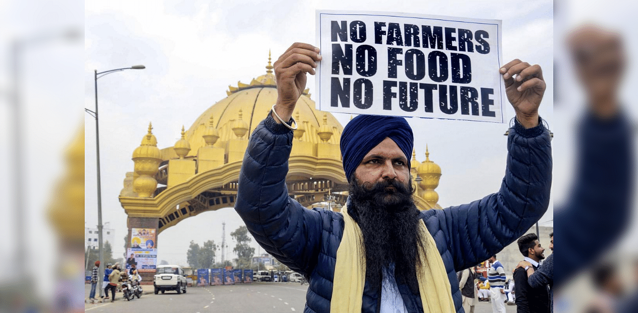 A farmer holds a placard during a protest in support of the nationwide strike, called by the farmer unions to press for repeal of the Centre's Agri laws, in Amritsar, Tuesday, Dec. 8, 2020. Credit: PTI Photo