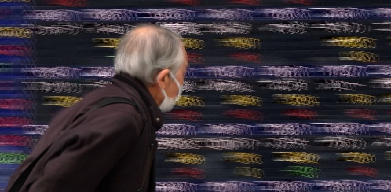 A pedestrian walks past an electronic quotation board displaying numbers of companies’ stock prices at the Tokyo Stock Exchange. Credit: AFP Photo