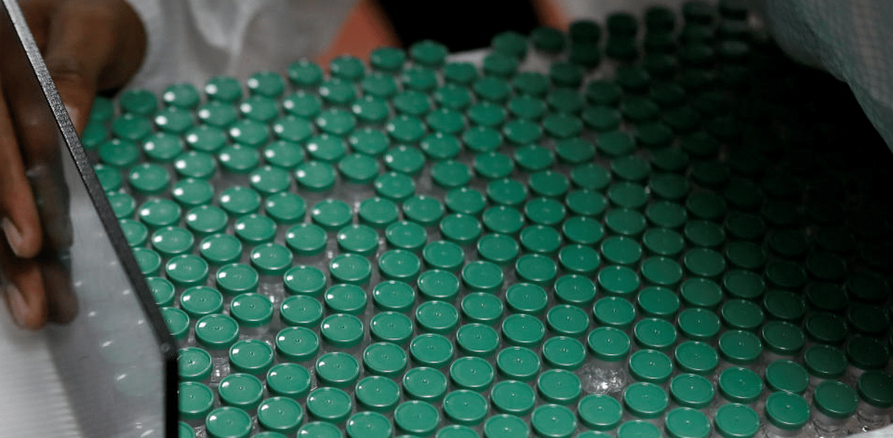 An employee in personal protective equipment (PPE) removes vials of AstraZeneca's COVISHIELD, coronavirus disease (COVID-19) vaccine from a visual inspection machine inside a lab at Serum Institute of India, in Pune. Credit: Reuters File Photo