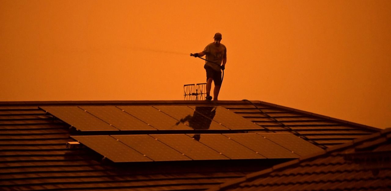 A resident uses a garden hose to wet down the house as high winds push smoke and ash from the Currowan Fire towards Nowra, New South Wales, Australia. Credit: Reuters Photo