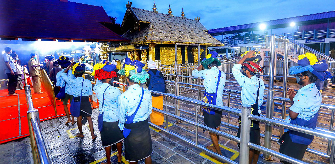 Devotees maintain social distance while standing in queues to offer prayers at Lord Ayyappa temple. Credit: PTI Photo