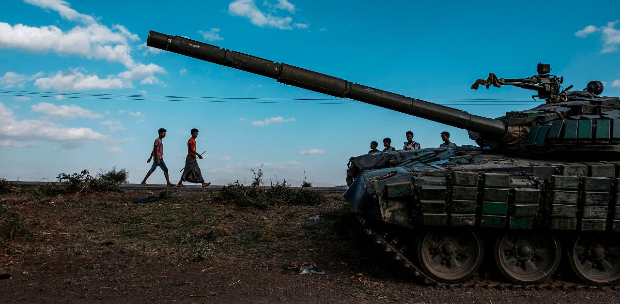 Youngsters walk next to an abandoned tank belonging to Tigrayan forces south of the town of Mehoni, Ethiopia. Credit: AFP Photo