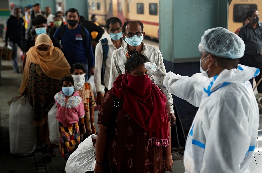 A health worker in personal protective equipment (PPE) checks the temperature of passengers amid the spread of the coronavirus disease (Covid-19), at a railway station in Mumbai. Credit: Reuters Photo