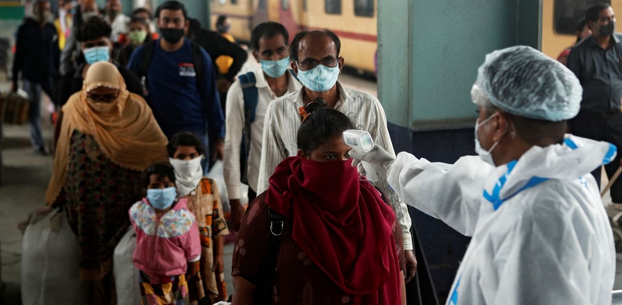 A health worker in personal protective equipment (PPE) checks the temperature of passengers amid the spread of the coronavirus disease, at a railway station in Mumbai on December 11, 2020. Credit: Reuters Photo