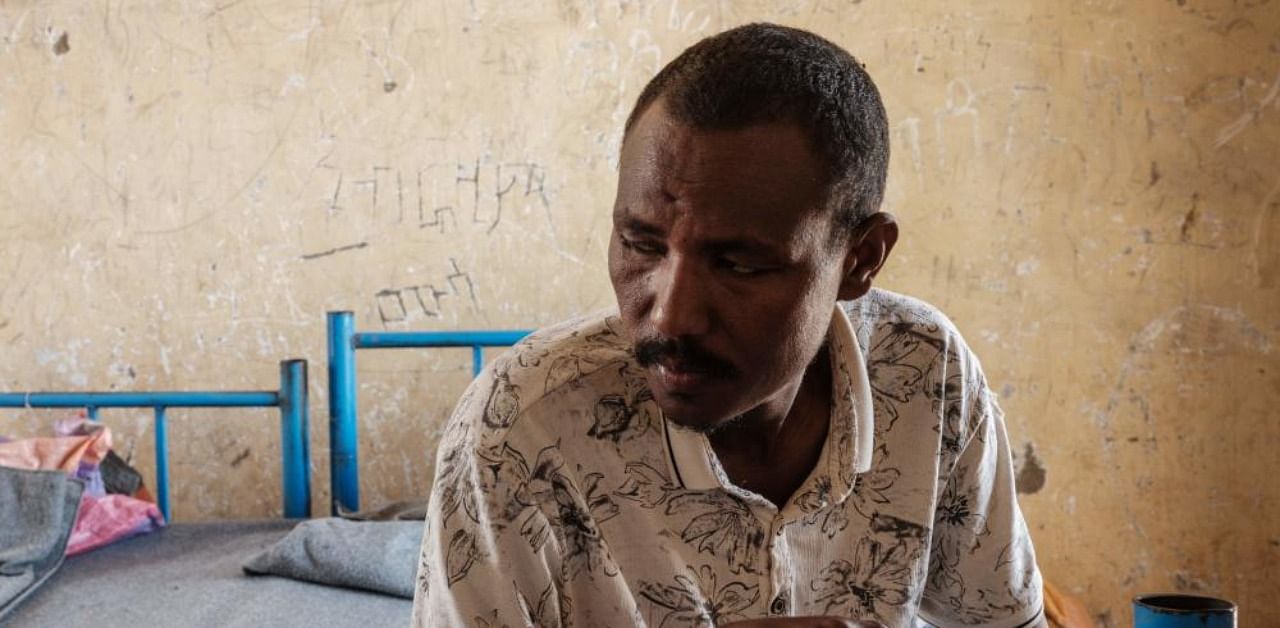 Kheder Adam, an Eritrean refugee who fled the Ethiopia's Tigray conflict, poses on his bed after an interview with AFP at the Border Reception Centre in Hamdayit. Credit: AFP photo.