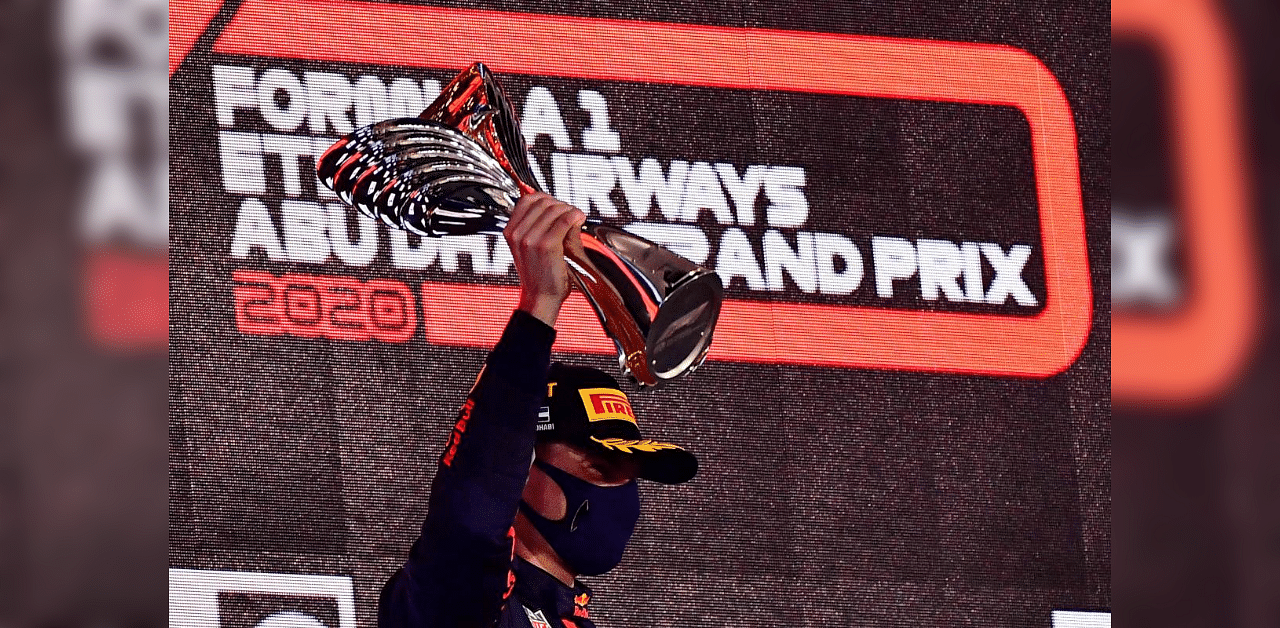 Red Bull's Dutch driver Max Verstappen raises his 1st-place trophy on the podium after the Abu Dhabi Formula One Grand Prix at the Yas Marina Circuit in the Emirati city of Abu Dhabi on December 13, 2020. Credit: AFP Photo