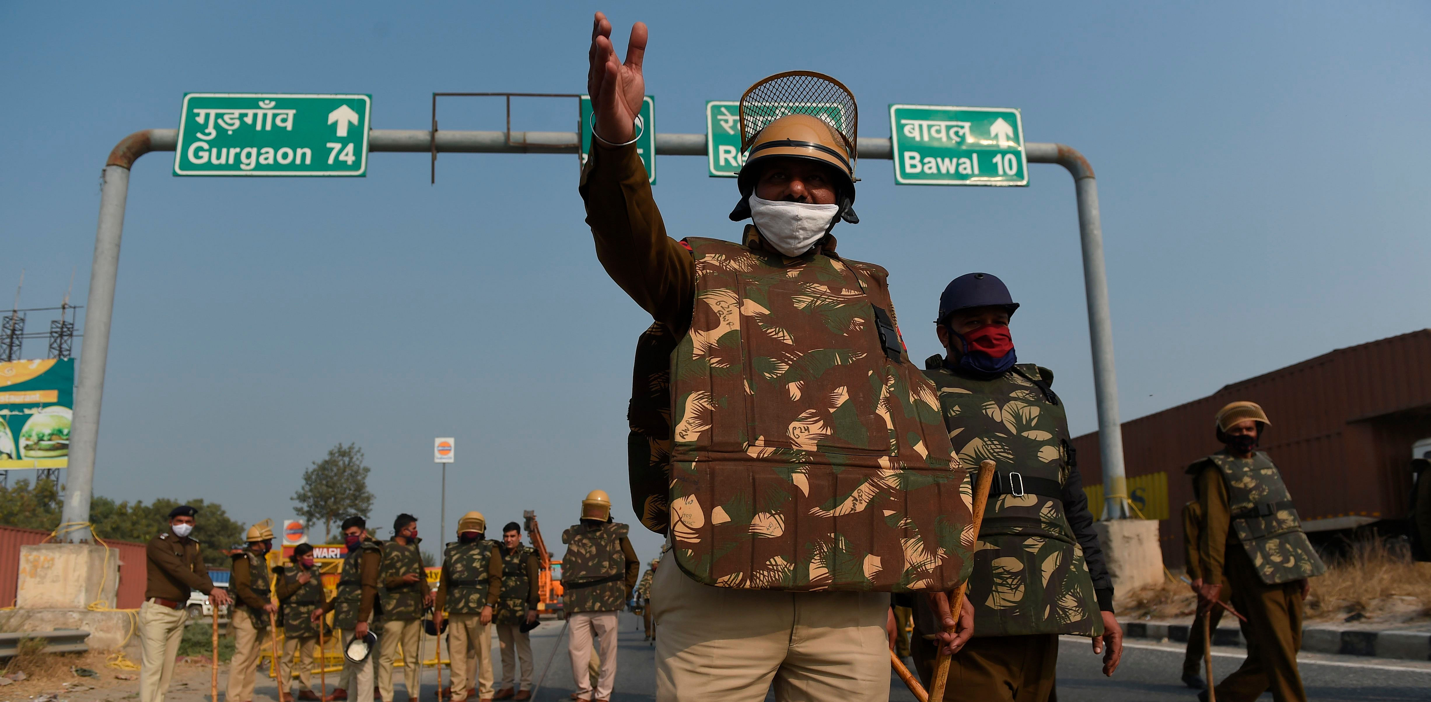 Police personnel stand along a highway on the Haryana-Rajasthan border to stop farmers from joining protests in Delhi against the recent agricultural reforms. Credit: AFP