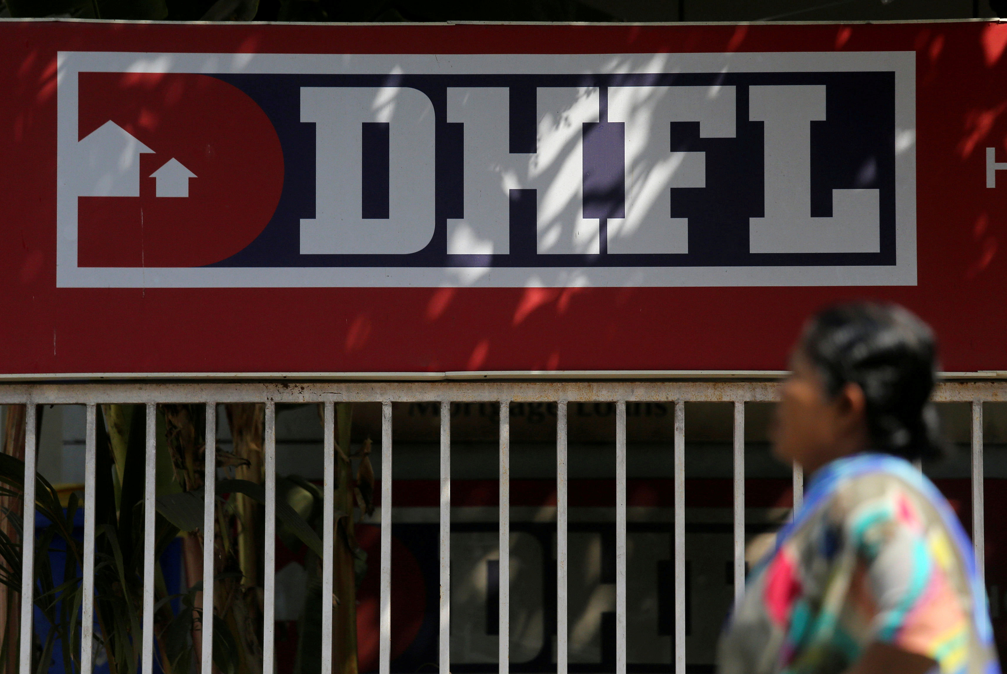 A woman walks past a Dewan Housing Finance Corporation Ltd. (DHFL) sign. Credit: Reuters Photo
