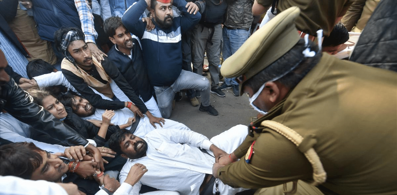 A policeman tries to detain Samajwadi Party workers protesting against the Centre's new farm laws, in Lucknow. Credit: PTI