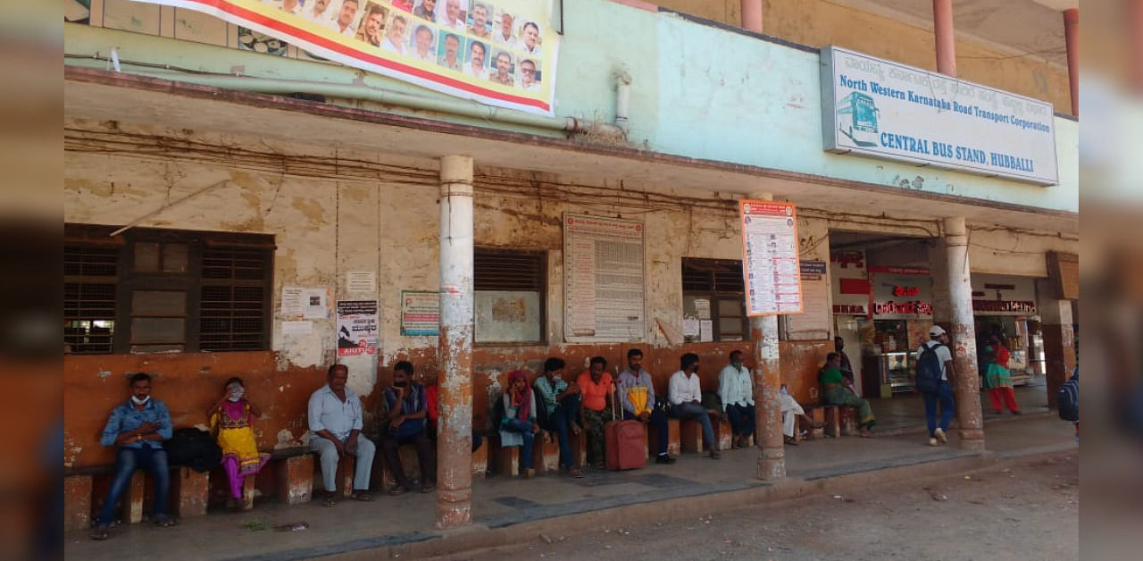 Passengers wait for a bus at Old-Bus stand in Hubballi on Monday. Bus services are expected to return to normalcy by afternoon. Credit: DH photo