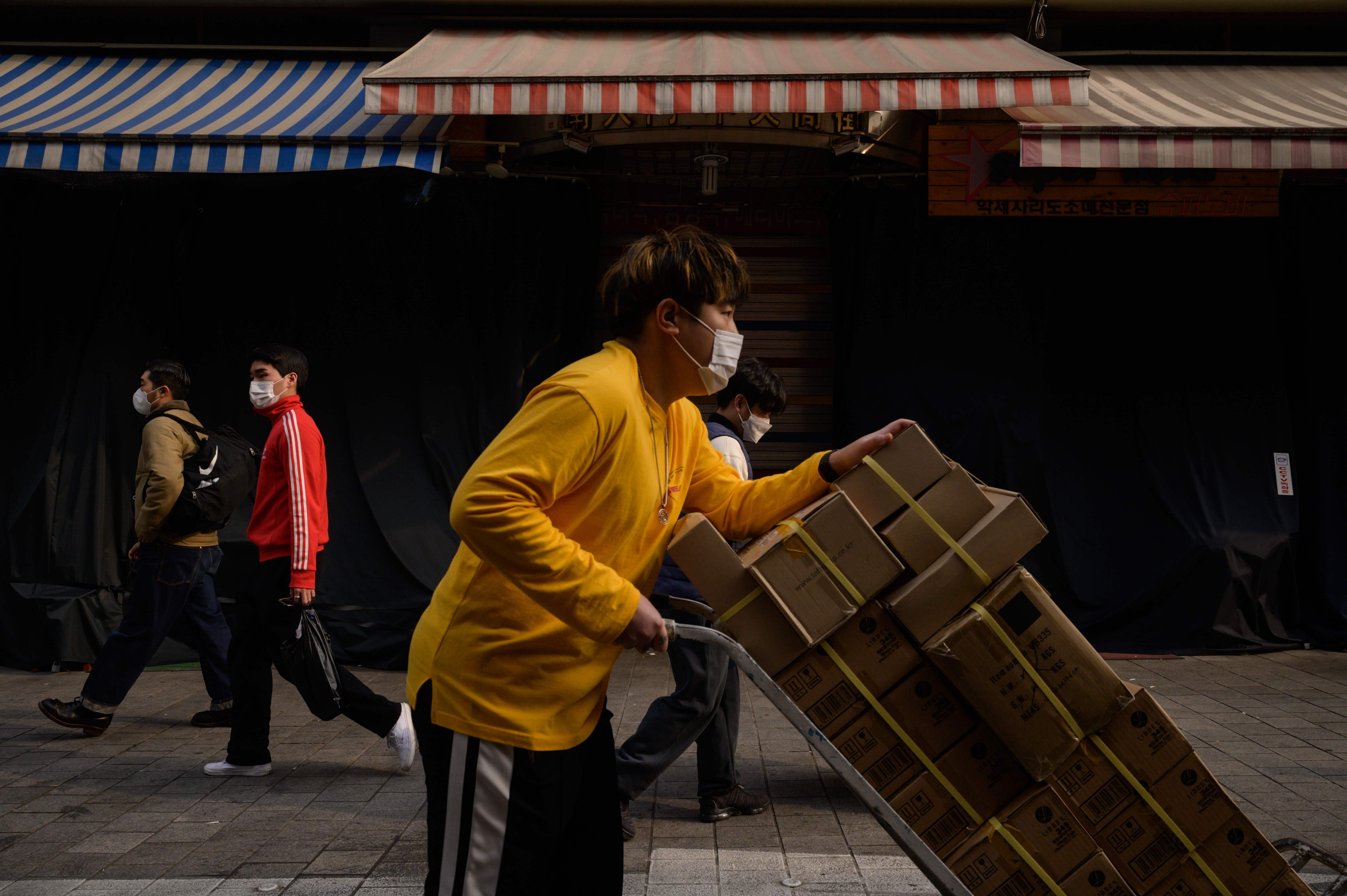 Shoppers and delivery workers walk past a row of stalls closed following a Covid-19 coronavirus cluster there, at Namdaemun market in Seoul. Credit: AFP Photo