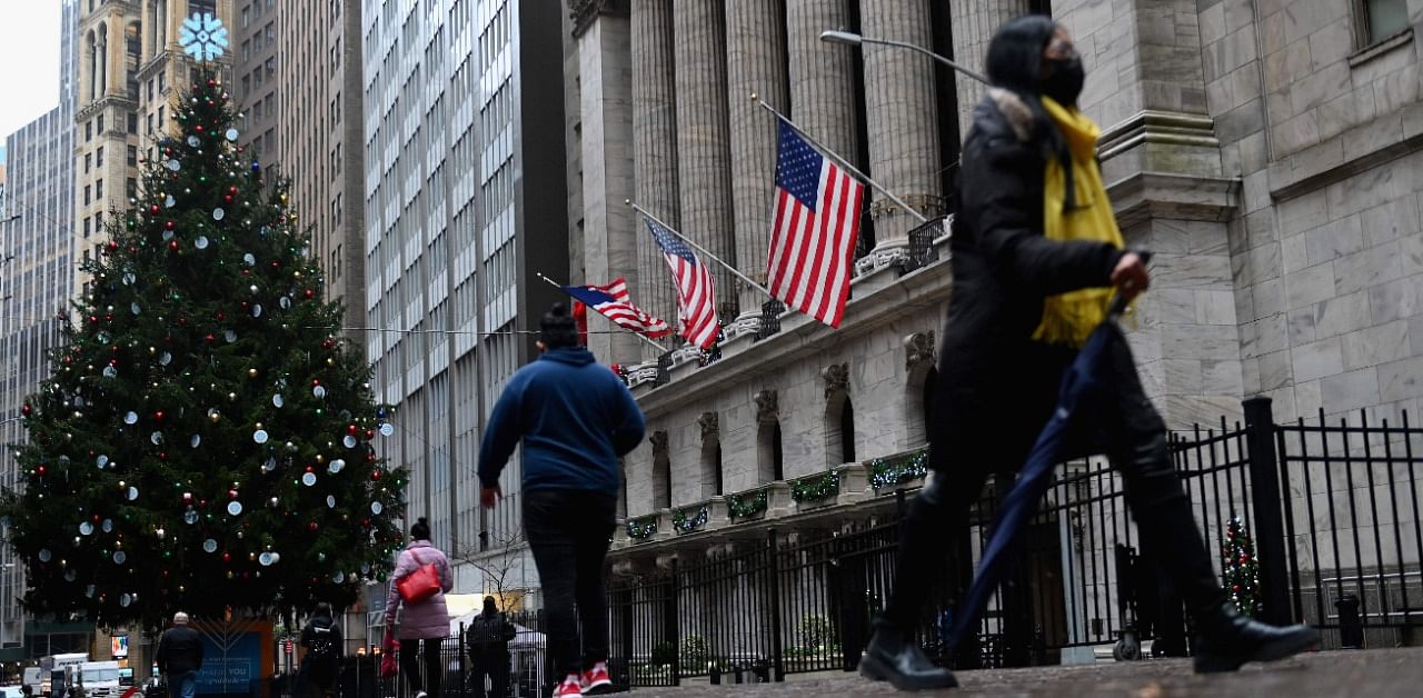 People walk past the New York Stock exchange (NYSE) at Wall Street after heavy rainfall. Credit: AFP Photo