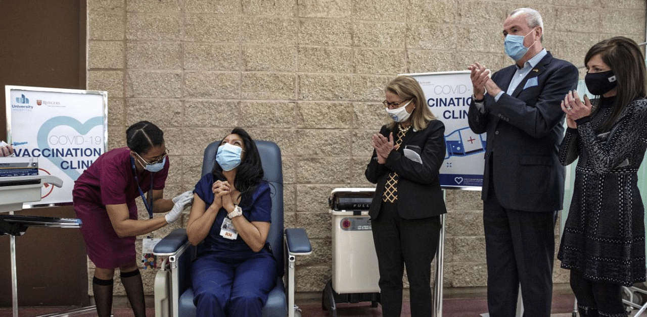 New Jersey Gov. Phil Murphy, second from right, watches as nurse Maritza Beniquez, seated, reacts after receiving the Pfizer-BioNTech Covid-19 vaccine, at University Hospital, in Newark, NJ. Credit: AP/PTI