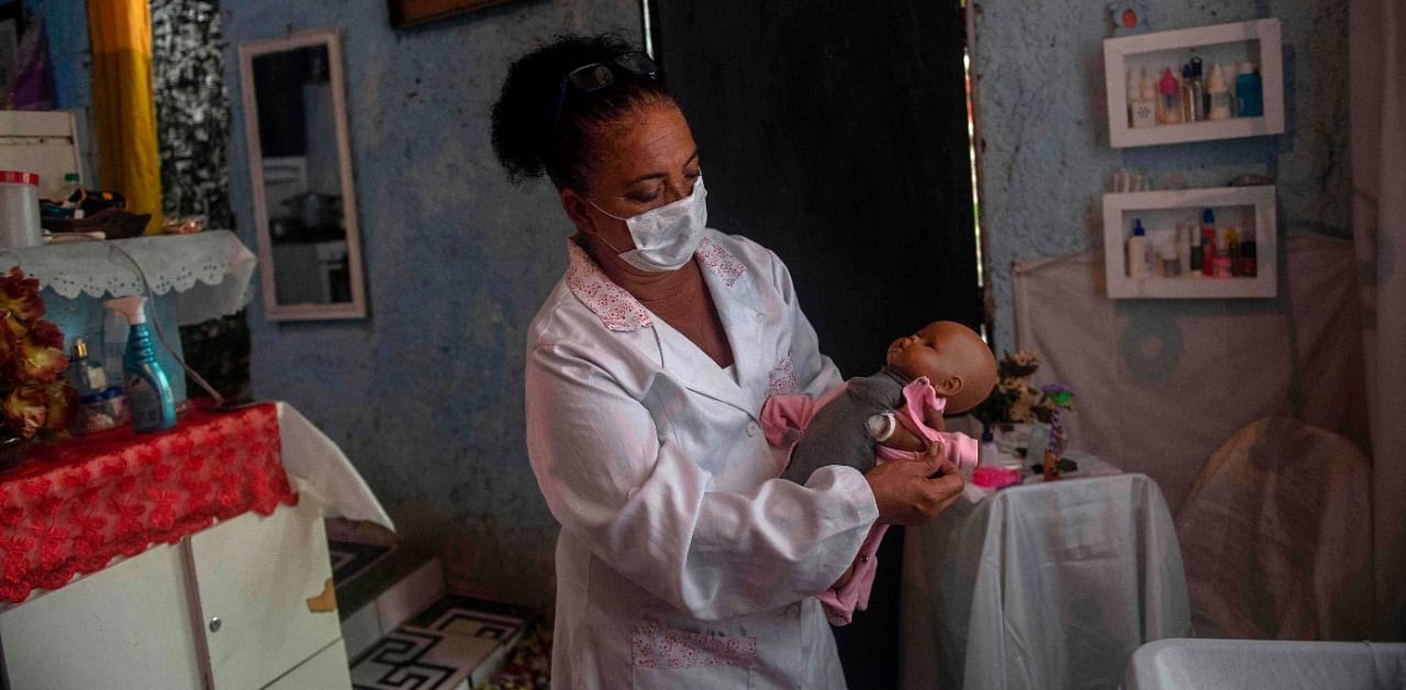 Suelen da Silva -- who lost her job in April, shortly after the coronavirus pandemic arrived in Brazil -- checks a doll at her 'Doll Hospital' located in her house in Niteroi, Rio de Janeiro state, Brazil, on December 10, 2020. Credit: AFP Photo