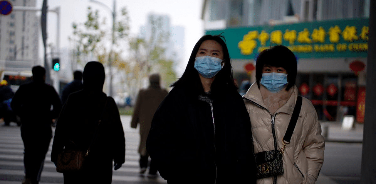 People wearing masks walk across a street, almost a year after the start of the coronavirus disease (COVID-19) outbreak, in Wuhan, Hubei. Credit: Reuters Photo
