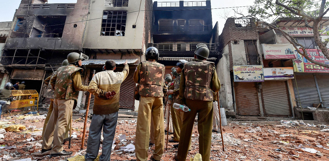 Security personnel look at a house set abalze by miscreants, in Bhagirathi Vihar area of the riot-affected north east Delhi. Credit: PTI File Photo