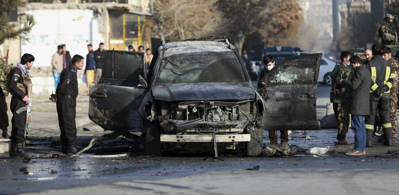 Afghan security personnel inspect a damaged vehicle after a bomb blast in Kabul, Afghanistan. Credit: AP/PTI.