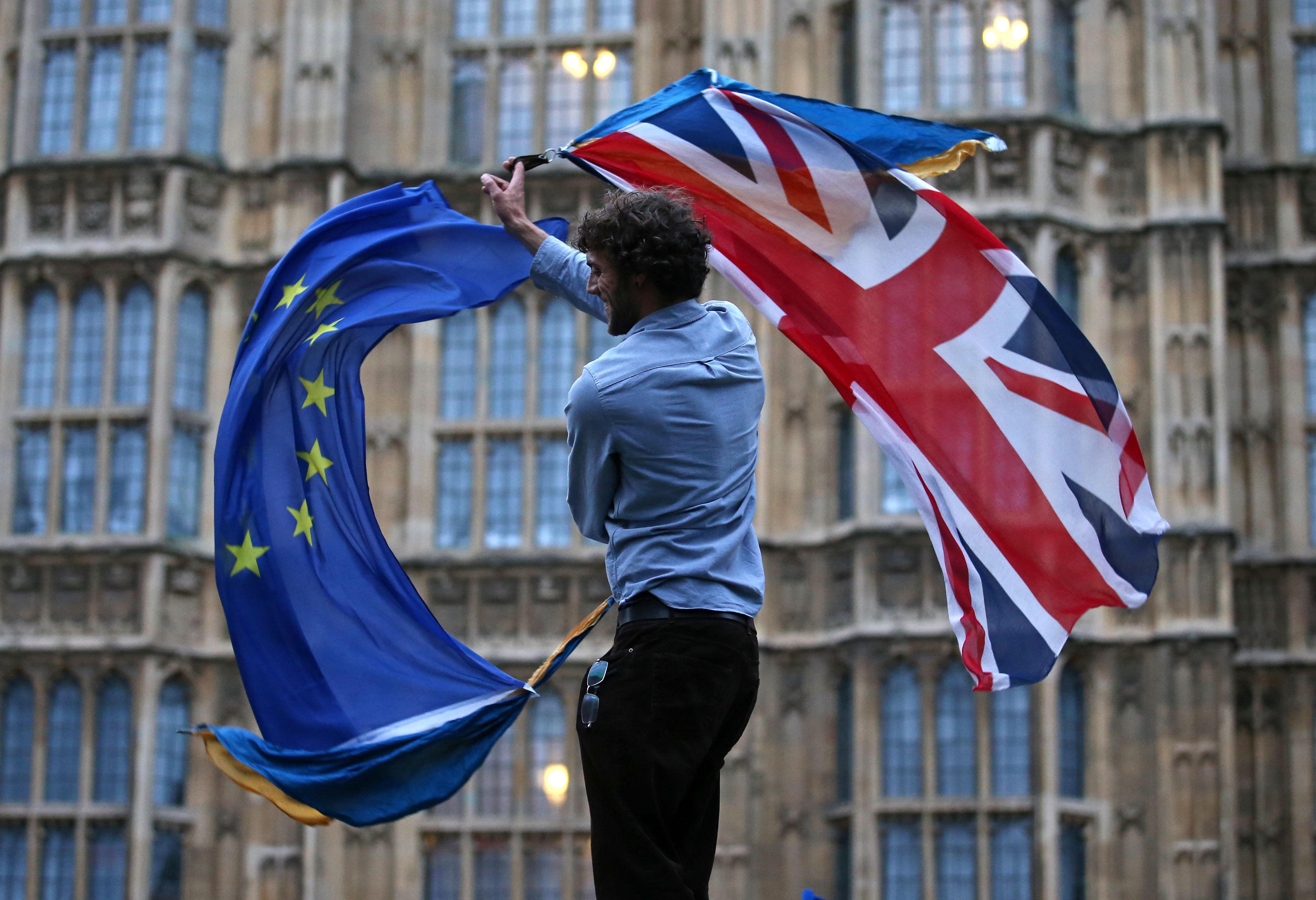 In this file photo taken on June 28, 2016 A man waves both a Union flag and a European flag together on College Green outside The Houses of Parliament at an anti-Brexit protest in central London on June 28, 2016. - Britain on December 17, 2020 sounded a more pessimistic note over the outcome of last-ditch Brexit trade talks with the European Union, saying a "no-deal" scenario was still on the cards. Prime Minister Boris Johnson's spokesman said negotiators from both sides were working to "bridge the gaps that remain", as the EU indicated a deal was "difficult but possible" by Friday. Credit: AFP Photo