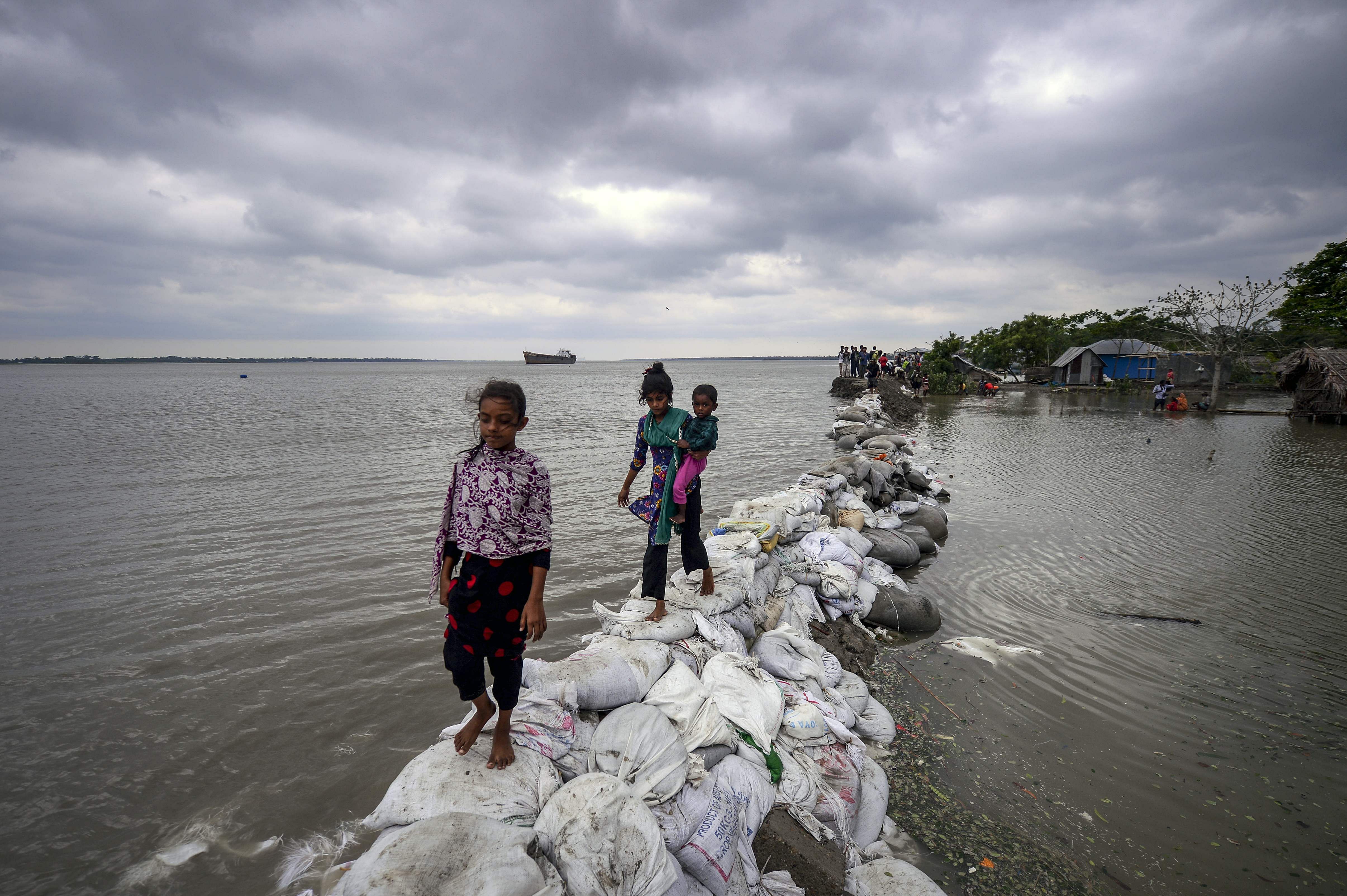   Bangladeshi children walk over the top of a sandbag embankment that was breached by high waters in Khulna on May 4, 2019, as Cyclone Fani reached Bangladesh. - Cyclone Fani, one of the biggest to hit India in years, barrelled into Bangladesh on May 4 after leaving a trail of deadly destruction in India. Representative image/Credit: AFP Photo