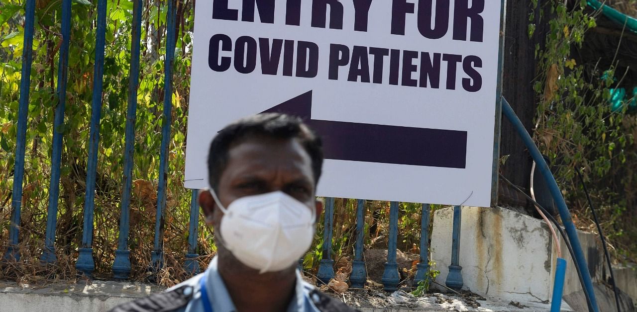 A private security personnel stands at the entrance gate for Covid-19 patients outside Gandhi Hospital in Hyderabad. Credit: AFP Photo