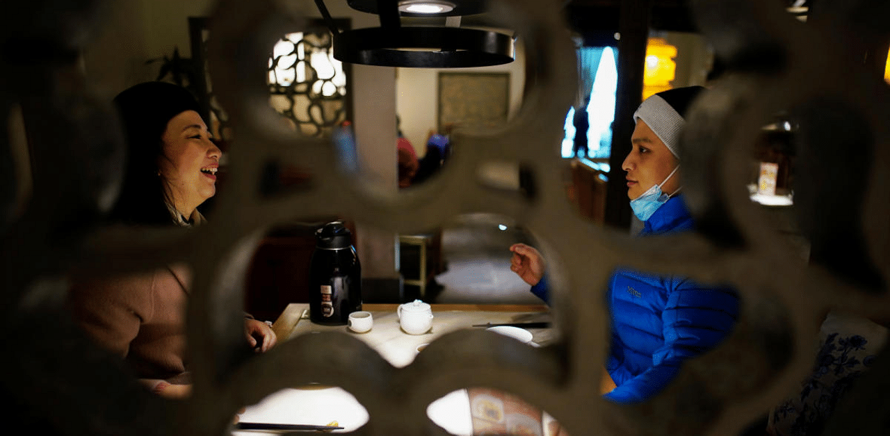 Duan Ling, 36, and her husband Fang Yushun chat in a restaurant, almost a year after the global outbreak of Covid-19 in Wuhan, Hubei province, China. Credit: Reuters