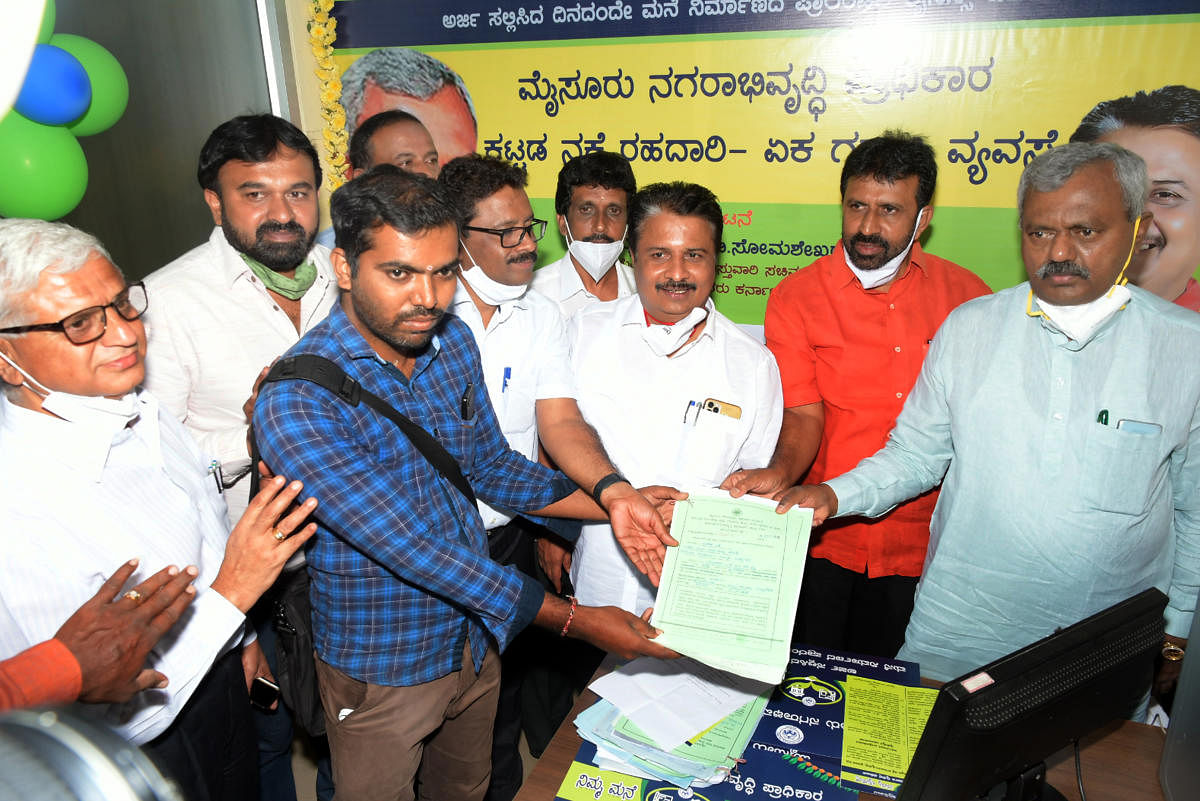 District In-charge Minister S T Somashekar launches 'Namma Mane-Namme License' at Mysuru Urban Development Authority in Mysuru on Thursday. MUDA Chairman H V Rajeev and Commissioner D B Natesh are seen. Credit: DH PHOTO