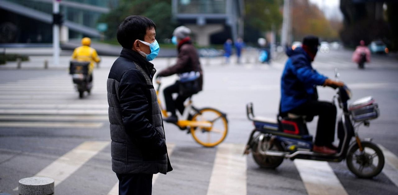 A man wearing a mask stands near a street, almost a year after the start of the coronavirus disease outbreak, in Wuhan. Credit: Reuters.