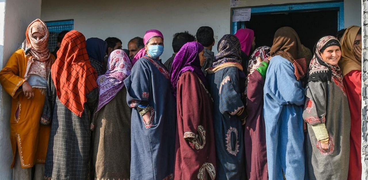 Residents stand in a queue to cast their votes outside a polling station during the eight and last phase of the District Development Council (DDC) elections, at Pattan in Baramulla district. Credit: PTI.