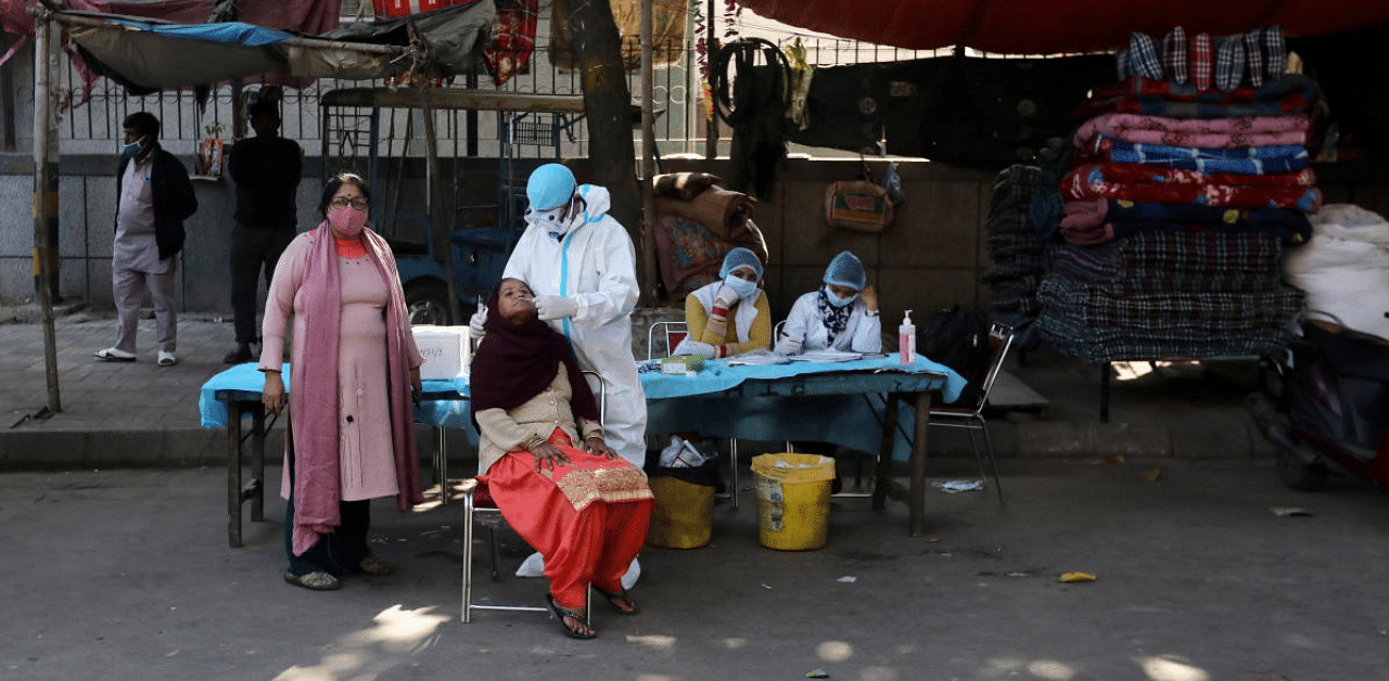 A healthcare worker collects a swab sample from a woman, in New Delhi. Credit: Reuters Photo