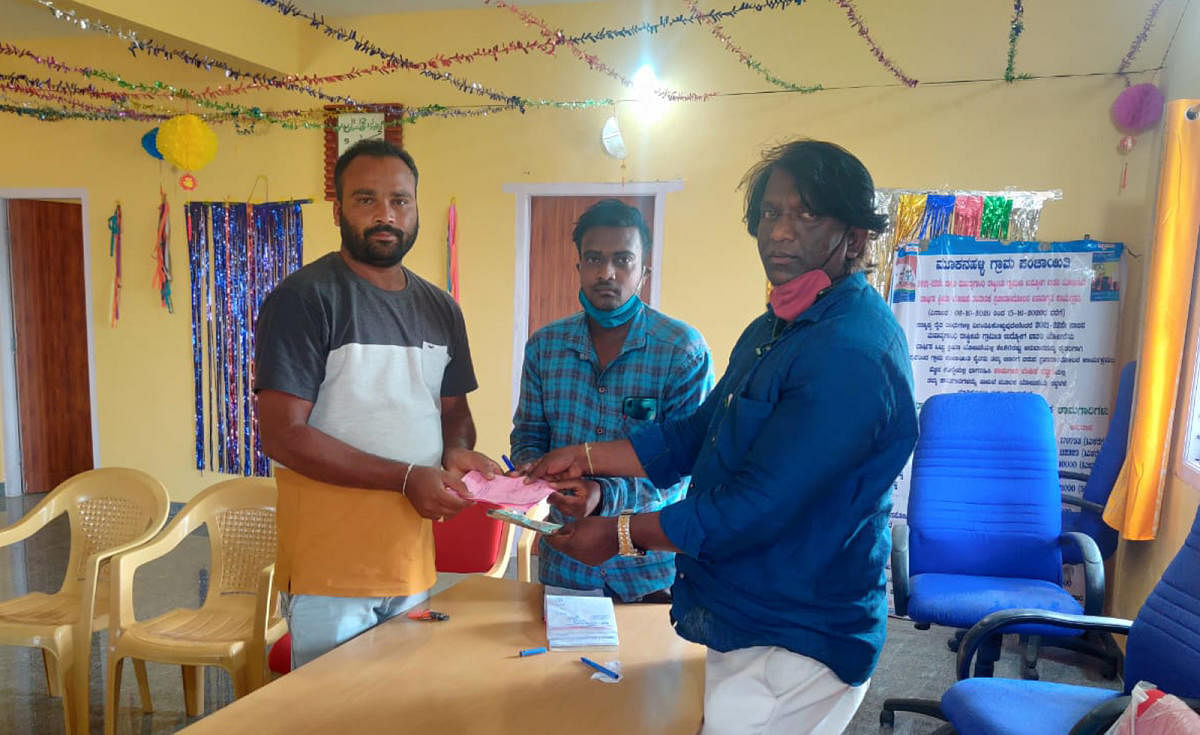 A Gram Panchayat candidate receives a tax paid certificate from PDO Srinivas at Mookanahalli in Hunsur taluk recently.