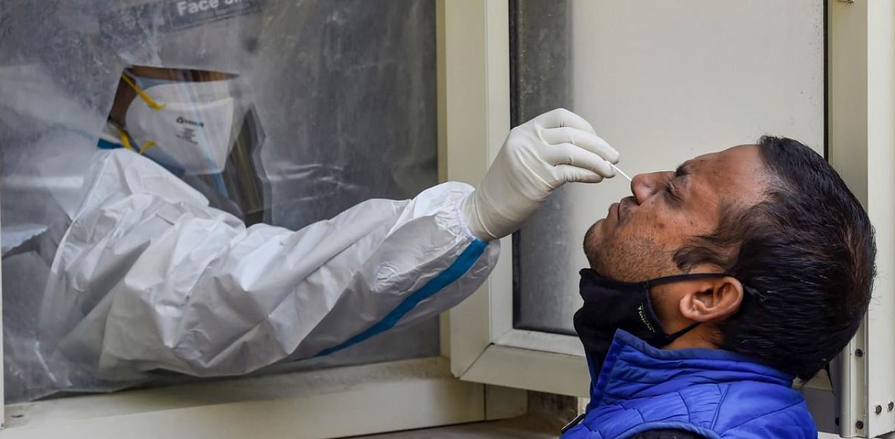 A health worker collects a sample from a man for Covid-19 test, in New Delhi. Credit: PTI.