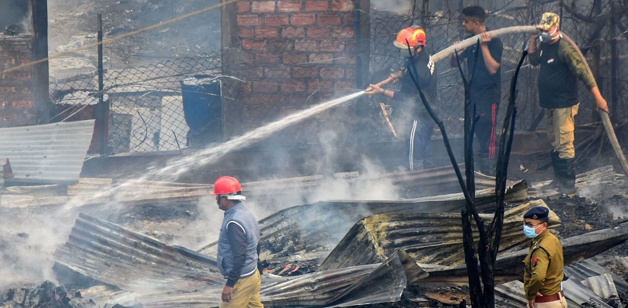 Fire fighters attempt to douse a fire that broke out in a residential area due to cylinder blast, at Jalukbari in Guwahati. Credit: PTI Photo