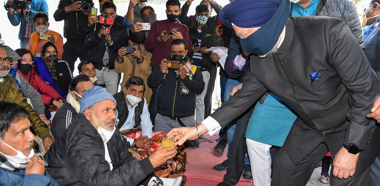Union Minister Hardeep Singh Puri serves juice to protestors agitating outside Chief Minister Arvind Kejriwal's residence, in New Delhi. Credit: PTI Photo