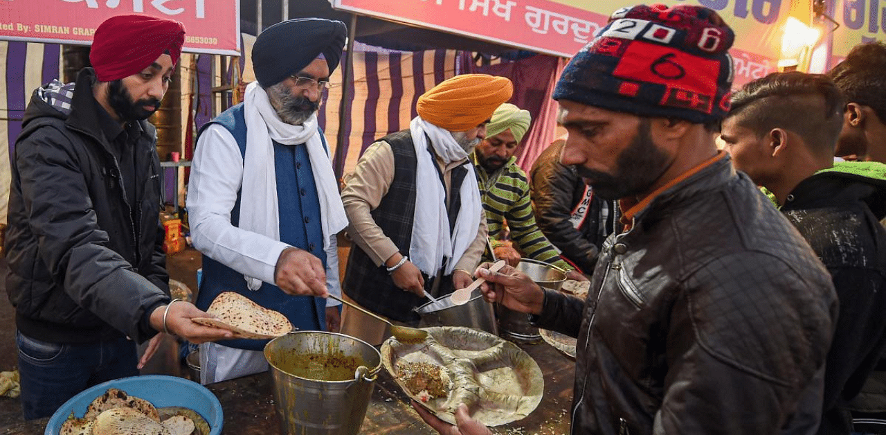 Delhi Sikh Gurdwara Management Committee President Manjinder Singh Sirsa serves food at Singhu border during farmers' sit-in protest against the Centre's farm reform laws, in New Delhi. Credit: PTI