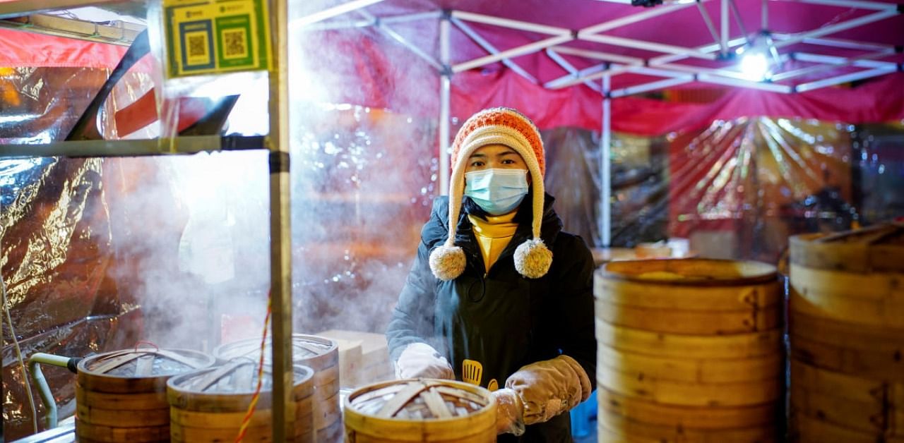 Jiang Honghua, 34, poses for a picture at her food stall almost a year after the global outbreak of Covid-19 in Wuhan, Hubei province, China. Credit: Reuters.