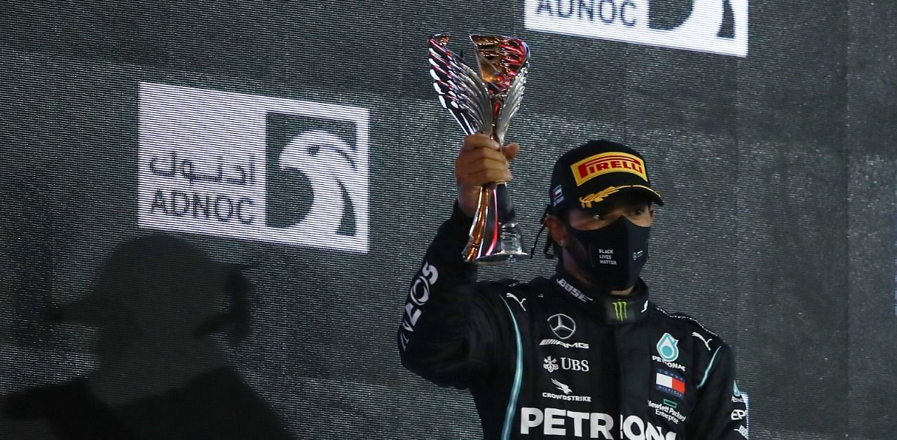 Mercedes' British driver Lewis Hamilton raises his 3rd-place trophy on the podium after the Abu Dhabi Formula One Grand Prix at the Yas Marina Circuit. Credit: AFP Photo