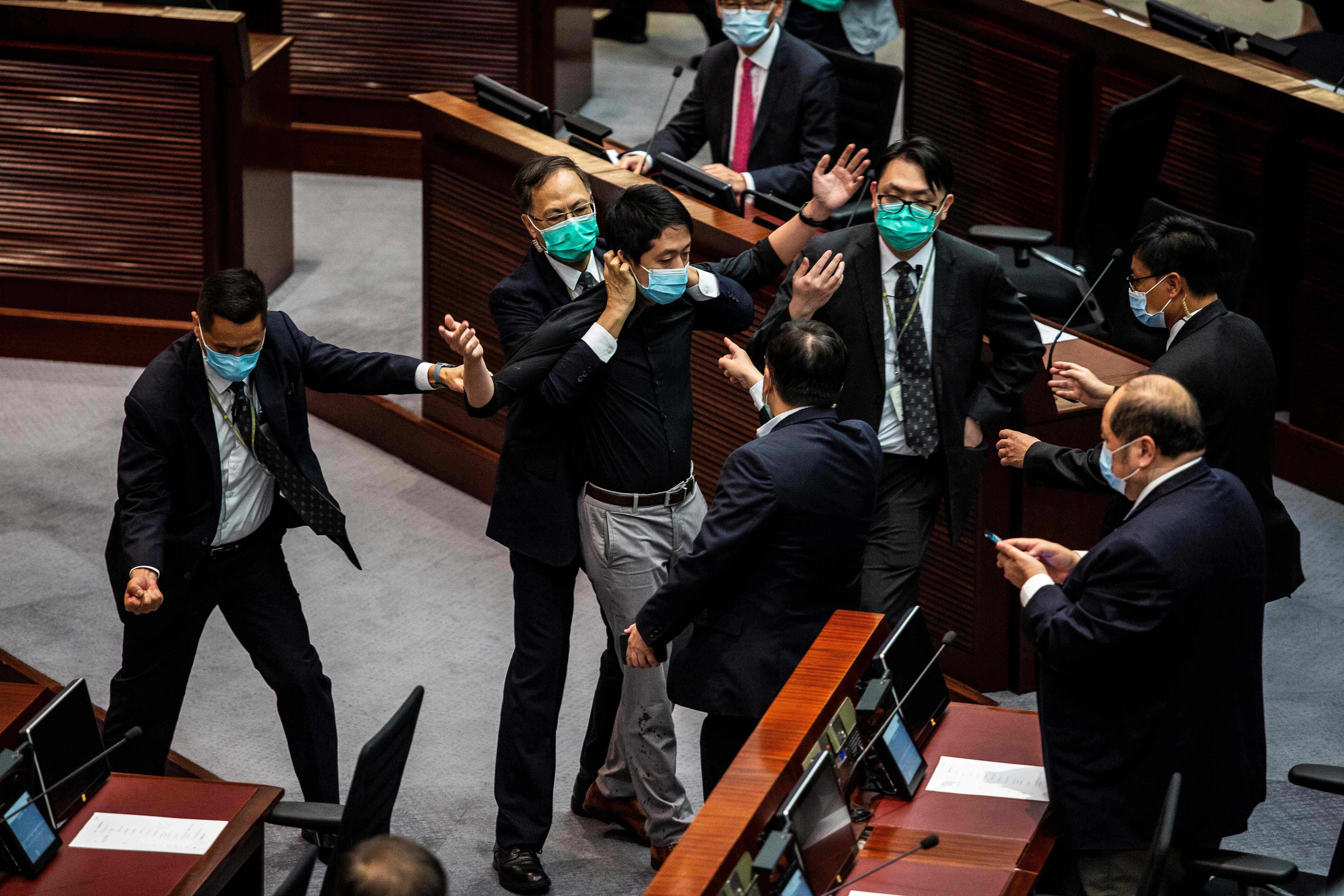 Pro-democracy legislator Ted Hui (C) is removed by security guards after throwing a jar containing a four-smelling liquid onto the floor during a debate on a law that bans insulting China's national anthem, at a session of the Legislative Council (Legco) in Hong Kong. Credit: AFP Photo