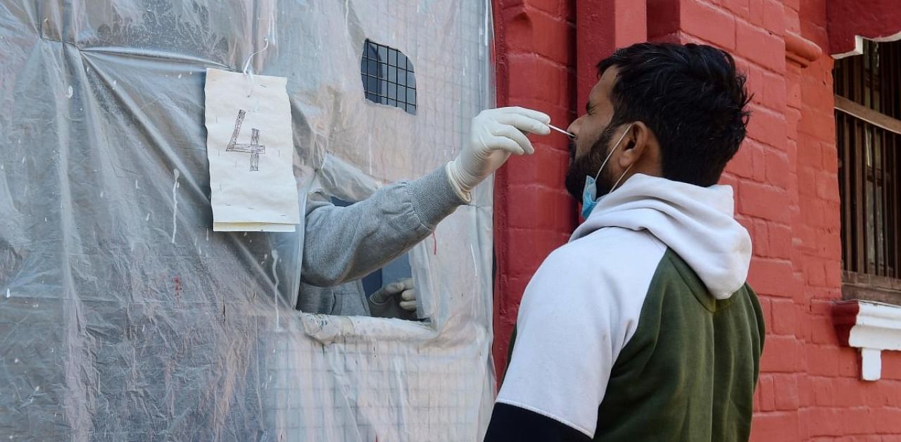 A health official takes a swab sample from a man to test for the Covid-19 coronavirus at a testing centre in Allahabad. Credit: AFP.