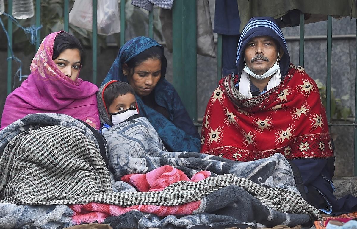 Members of a family wrapped in woolens sit at a road side, during a cold morning, in New Delhi. Credit: PTI