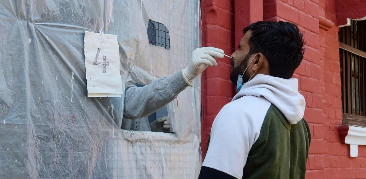 A health official takes a swab sample from a man to test for the Covid-19 at a testing centre in Allahabad. Credit: AFP Photo