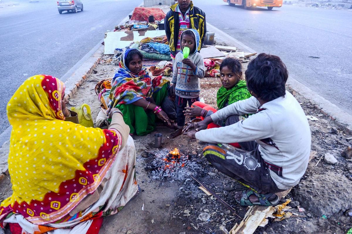 Homeless people gather around a small bonfire to warm themselves up during a cold winter morning in Delhi. Credit: AFP. 