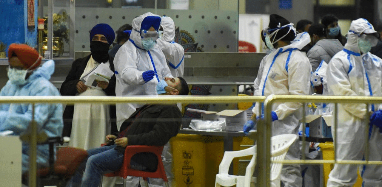 A health worker collects a swab sample from a passenger for the Covid-19 coronavirus test upon his arrival from London at Sri Guru Ram Dass Jee International Airport on the outskirts of Amritsar. Credit: AFP