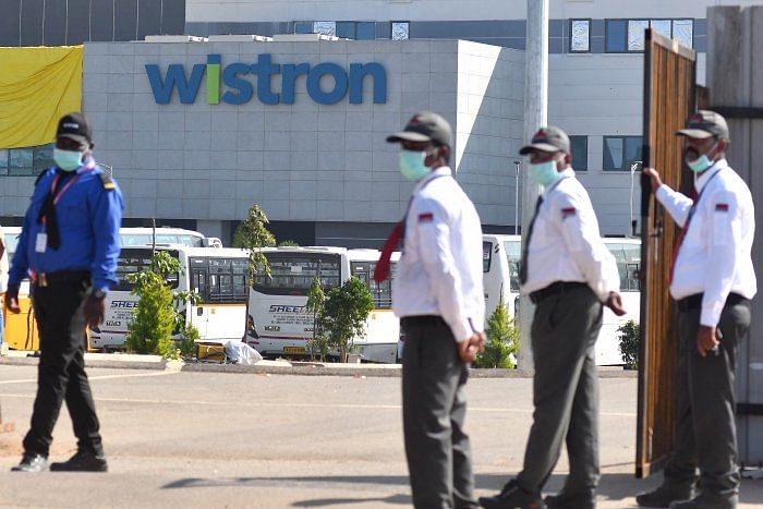 Security personnel stand guard outside Wistron Infocomm Manufacturing India Pvt Ltd at Narasapura area in Kolar. Credit: DH Photo/Pushkar V