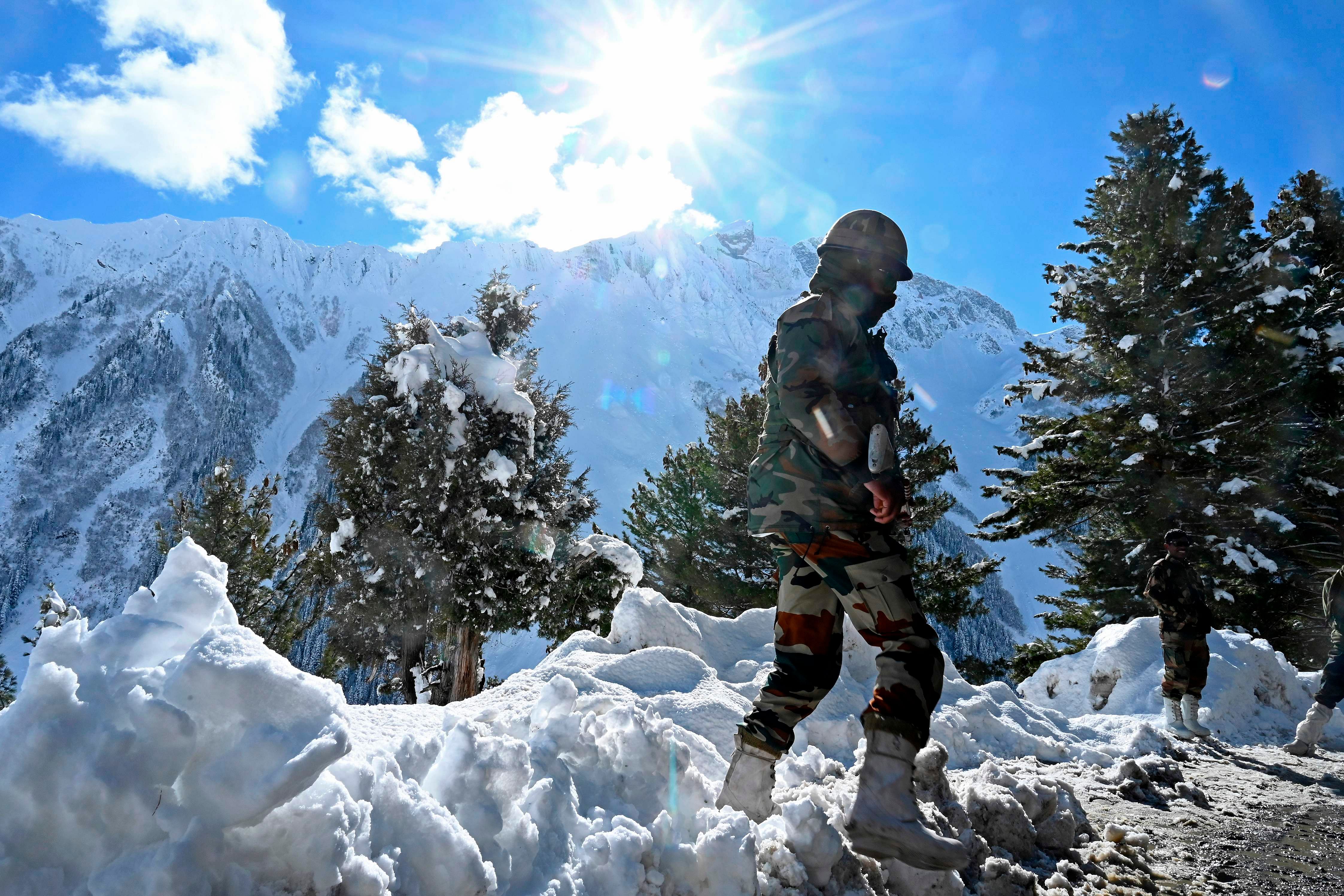 Indian army soldiers stand on a snow covered road after snowfall near Zojila mountain pass that connects Srinagar to the union territory of Ladakh. Credit: AFP Photo