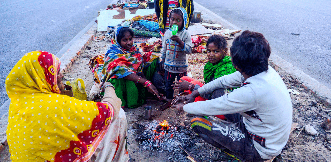 People gather around a small bonfire to warm themselves up during a cold winter morning on December 22. Credit: AFP