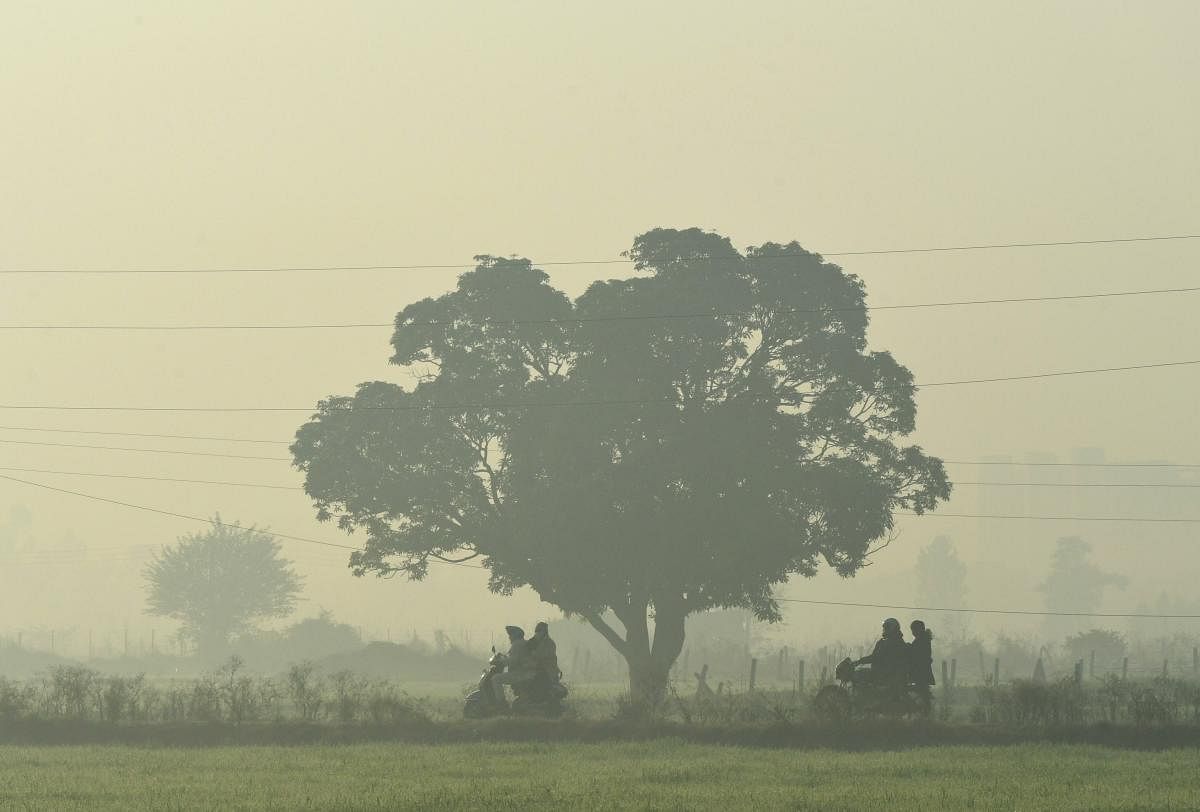 Commuters ride two-wheelers on their way to work, amid heavy fog in Sahibzada Ajit Singh Nagar district, on the outskirts of Chandigarh. Credit: PTI. 